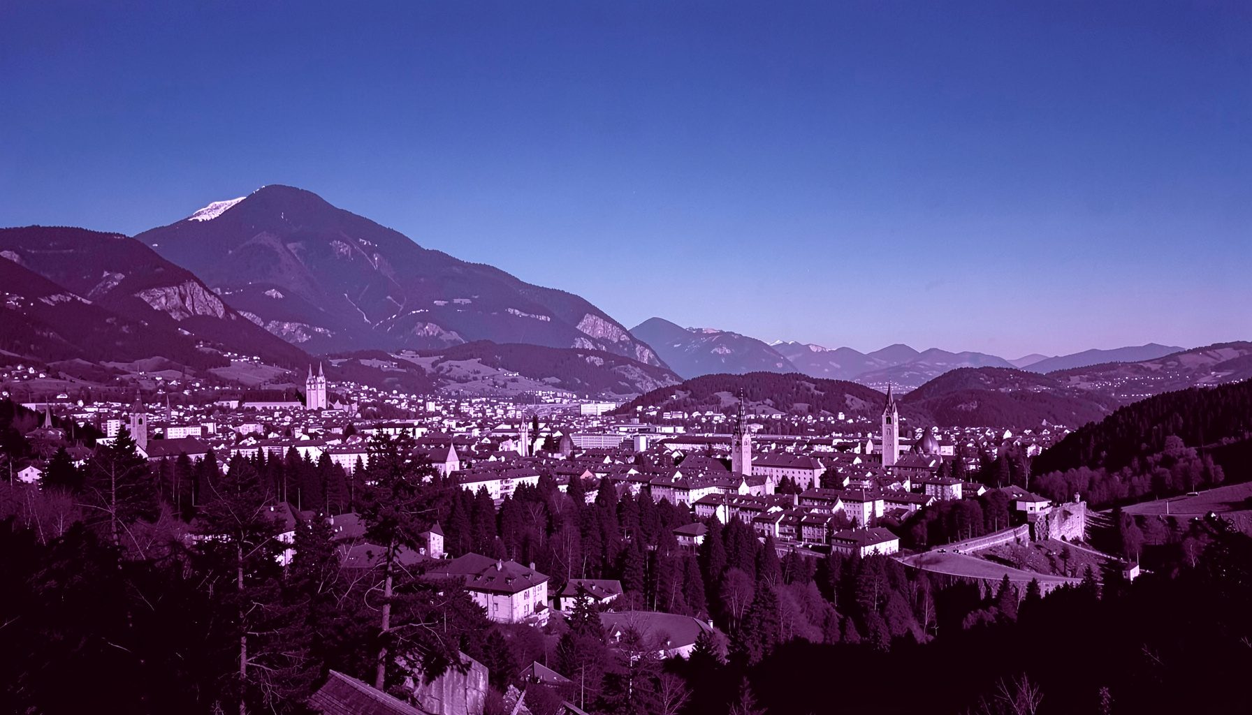 Unbeschriftetes Panorama der Stadt Innsbruck vor der Nordkette, klare Luft und tiefblauer Himmel.